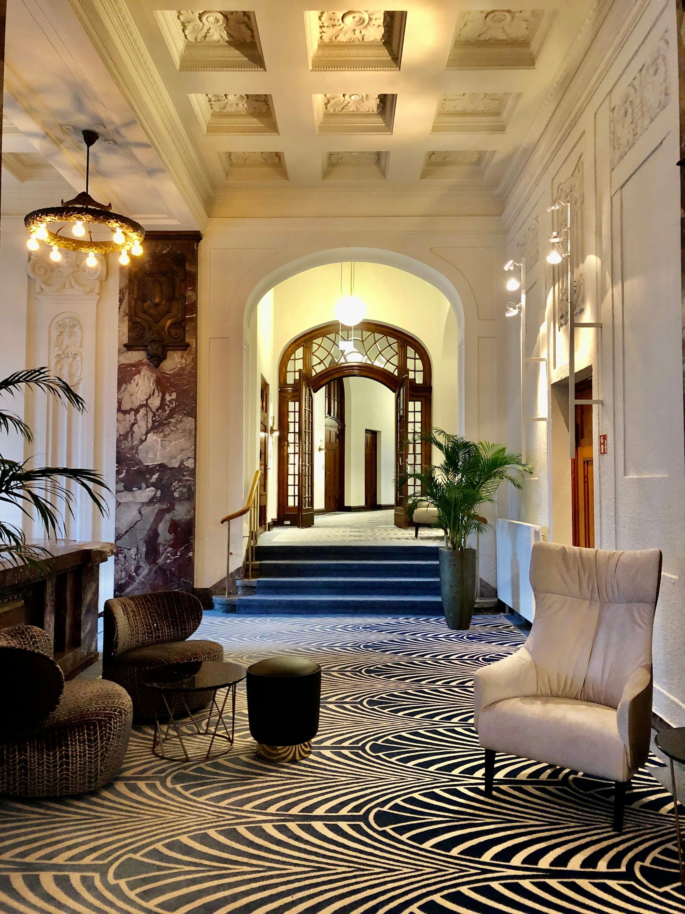Elegant marble hotel hallway with archways and a chandelier