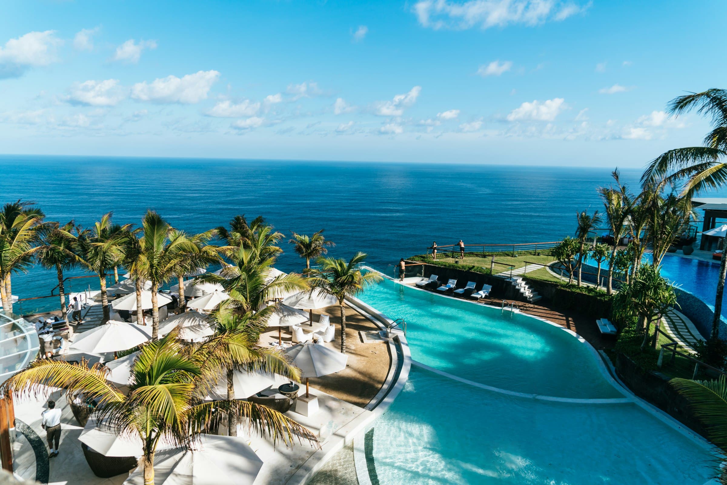 Aerial view of a cliffside infinity pool resort overlooking the ocean
